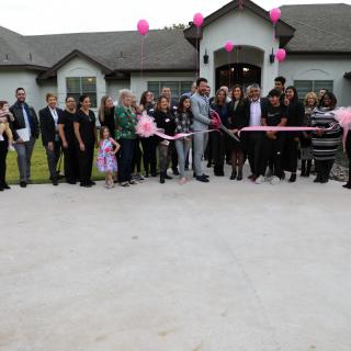 A group of people gathered in front of a building for a ribbon-cutting ceremony.