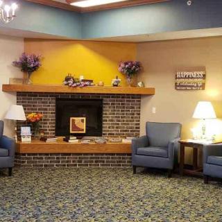 A cozy lobby area featuring a brick fireplace, comfortable chairs, and soft lighting.