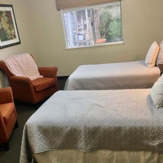 A cozy bedroom featuring two neatly made twin beds and an armchair by the window.