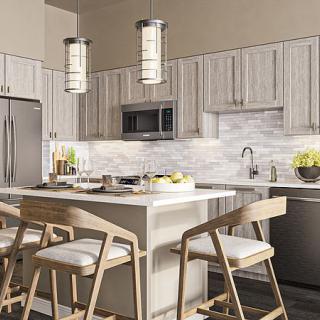 A modern kitchen featuring a central island with bar stools, stainless steel appliances, and pendant lighting.