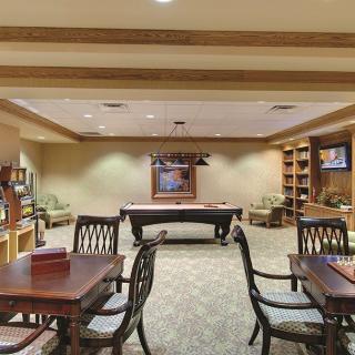 A cozy game room featuring a pool table, several seating areas, and bookshelves.