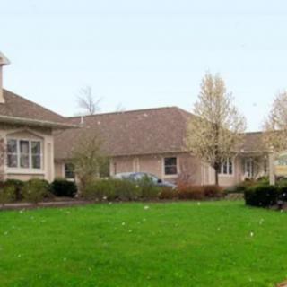 A suburban house with a well-maintained lawn and surrounding trees.