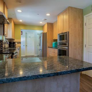 A modern kitchen with wooden cabinets, a sleek countertop, and stainless steel appliances.