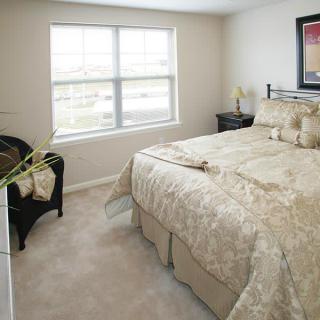 A cozy bedroom with a large bed, a window letting in natural light, and tasteful decor.