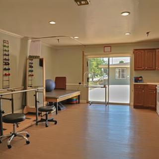 A spacious and well-lit therapy room equipped with exercise tools, designed for rehabilitation purposes.