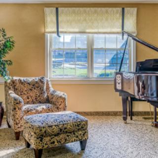 A cozy living room featuring a grand piano and a stylish armchair, perfect for relaxing moments.