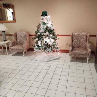 A festive Christmas tree surrounded by cozy chairs in a warmly decorated room.