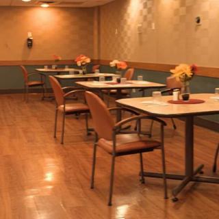 A cozy dining area with neatly arranged tables and chairs, adorned with floral centerpieces.