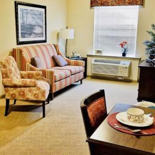 A cozy living room with a sofa, patterned chair, and dining table under a bright window.