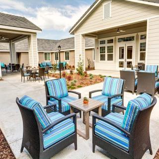 Cozy outdoor patio area with chairs and a table in a courtyard setting.