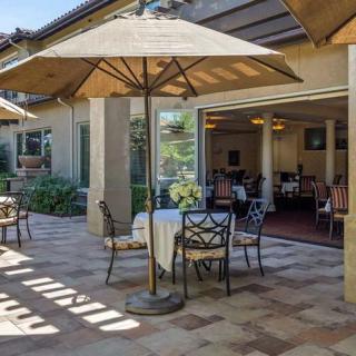 A sunny outdoor patio with tables, chairs, and large umbrellas at a restaurant.