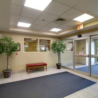 A well-lit lobby with plants, a bench, and large windows near the entrance.