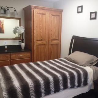 A cozy bedroom with a single bed, wooden furniture, and a striped blanket.