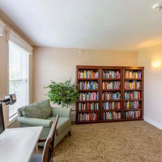 A cozy home office with a full bookshelf, armchair, and computer desk.
