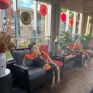 A festive indoor seating area adorned with Halloween decorations, including skeletons and autumn-themed decor.