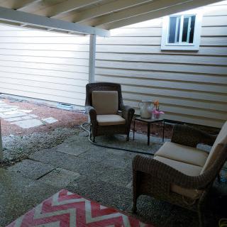 A cozy patio with two chairs, a small table, and a rug under a covered area.