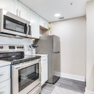 A compact modern kitchen featuring stainless steel appliances including a refrigerator, oven, and microwave.