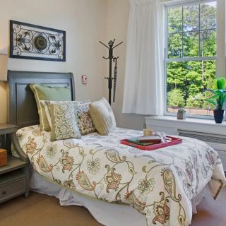 A cozy bedroom with a neatly made bed, decorative pillows, and a window view.