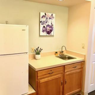 A small kitchen area with a refrigerator, sink, and wooden cabinets.