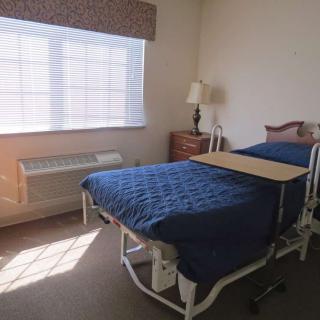 A hospital room with a bed and medical equipment by the window.