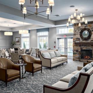 A spacious and elegantly decorated living room featuring comfortable seating, modern lighting, and a cozy fireplace.