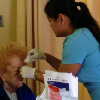 A healthcare professional attends to an elderly patient in a medical setting.