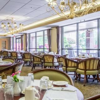 A spacious and elegantly decorated dining area with multiple tables and chairs, set for service.