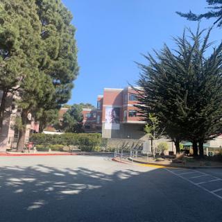 A peaceful scene featuring a building surrounded by trees under a clear blue sky.