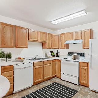 A cozy, modern kitchen featuring wooden cabinets and essential appliances.