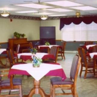 A dining area with neatly arranged tables and chairs, featuring a piano in the corner.