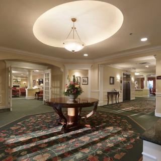 An elegant hotel lobby featuring a chandelier, floral-patterned carpet, and tasteful furnishings.