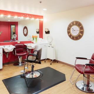 A modern hair salon interior with red and white decor, styling chairs, and mirrors.