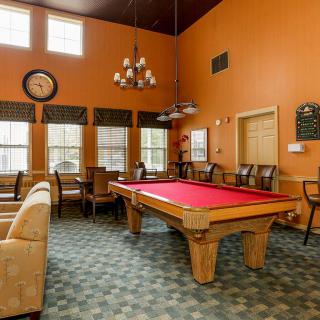A cozy game room with a red pool table and comfortable seating.