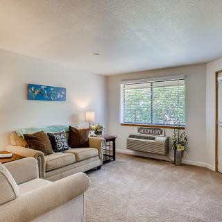 A cozy living room with a comfortable sofa, artwork on the wall, and a large window providing natural light.