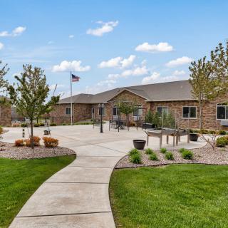 A well-maintained building with a welcoming pathway, surrounded by landscaped lawns and trees under a partly cloudy sky.