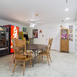 A room with a round table, wooden chairs, and a vending machine.