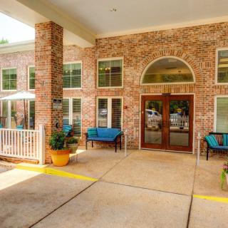The entrance to a brick building with outdoor seating and potted plants.