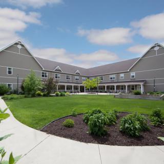 A modern building with a landscaped courtyard under a partly cloudy sky.