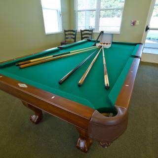 A pool table set up with cue sticks, ready for a game of billiards in a well-lit room.
