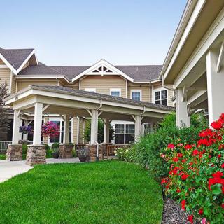 A beautifully landscaped residential building with lush green lawns and vibrant flower beds.
