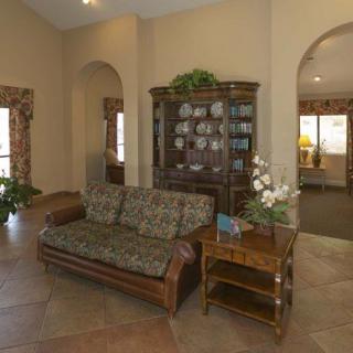 A cozy living room with a patterned sofa, decorative cabinet, and indoor plants.