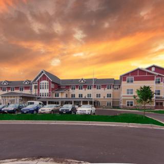 A residential building with a parking lot in front, set against a dramatic sunset sky.