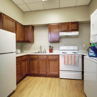 A modern kitchen featuring wooden cabinets, a refrigerator, and essential appliances.