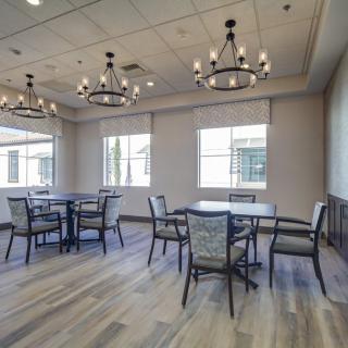 A modern dining room with elegant chandeliers and multiple tables and chairs.