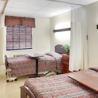A hospital room with two patient beds and basic amenities.