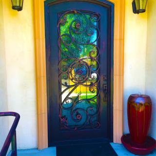 A decorative entrance with an ornate door featuring stained glass and intricate ironwork.