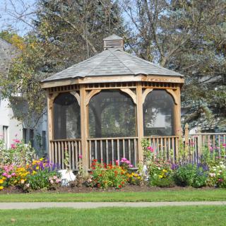 A wooden gazebo surrounded by a colorful garden.