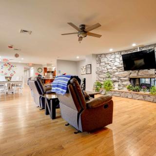 A cozy living room featuring comfortable recliners, a stone fireplace with a mounted television, and wooden flooring.