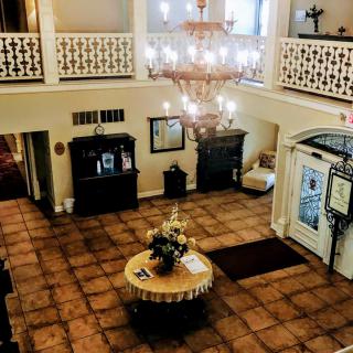 A grand hotel lobby featuring a large chandelier and an elegant table centerpiece.