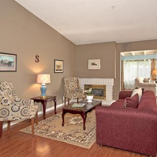 A cozy living room with a maroon sofa, patterned armchairs, and a fireplace.